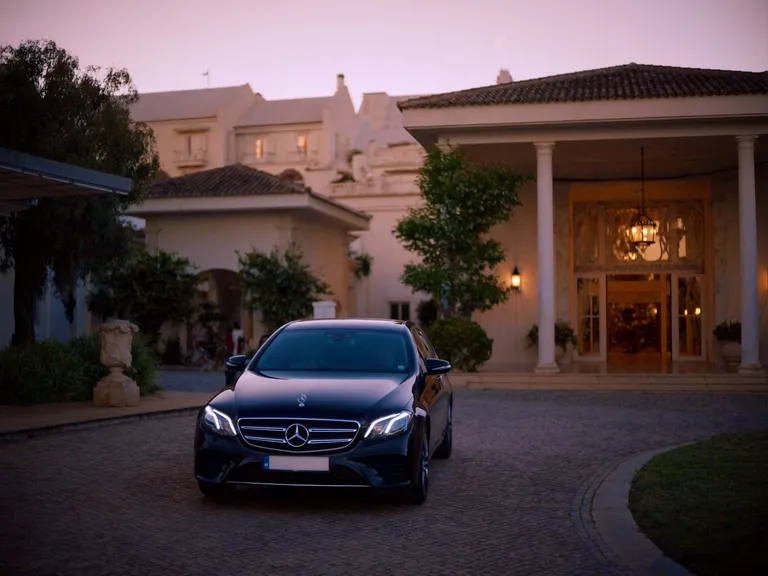Mercedes E-Class Sedan preto à entrada de um resort no Algarve ao entardecer